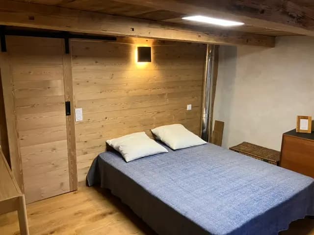 Chambre avec lit double, couvre-lit bleu et tête de lit en vieux bois