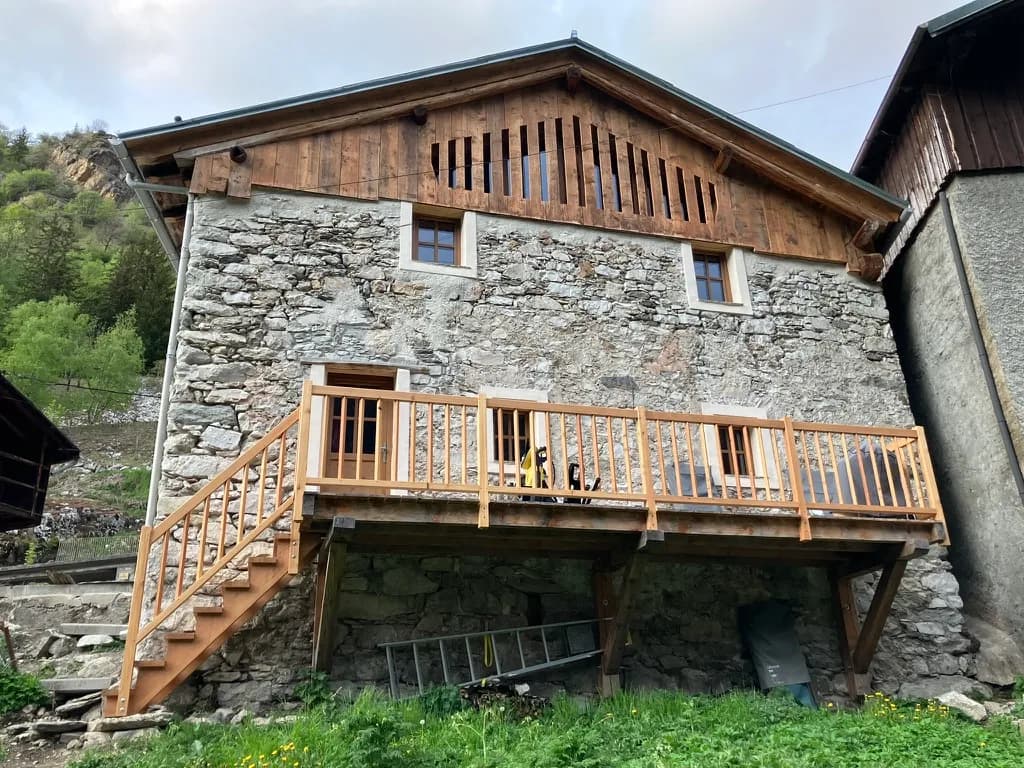 Escalier en bois menant à la terrasse en pierre du chalet