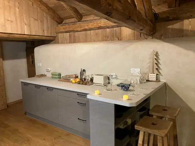 Grande cuisine grise et bar sous les poutres anciennes