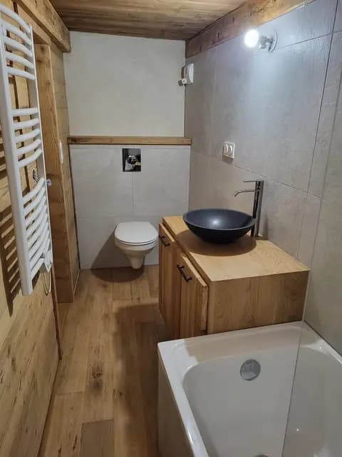 Salle de bain avec baignoire, vasque noire sur meuble chêne