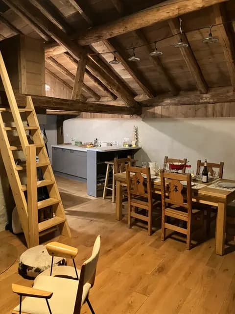 Poutres apparentes, table en bois et chaises autour d'un poêle dans le séjour