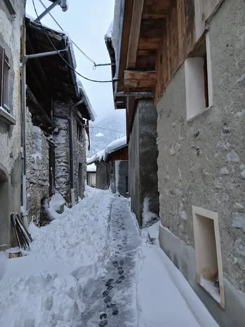 Escalier enneigé bordé de chalets en pierre et bois