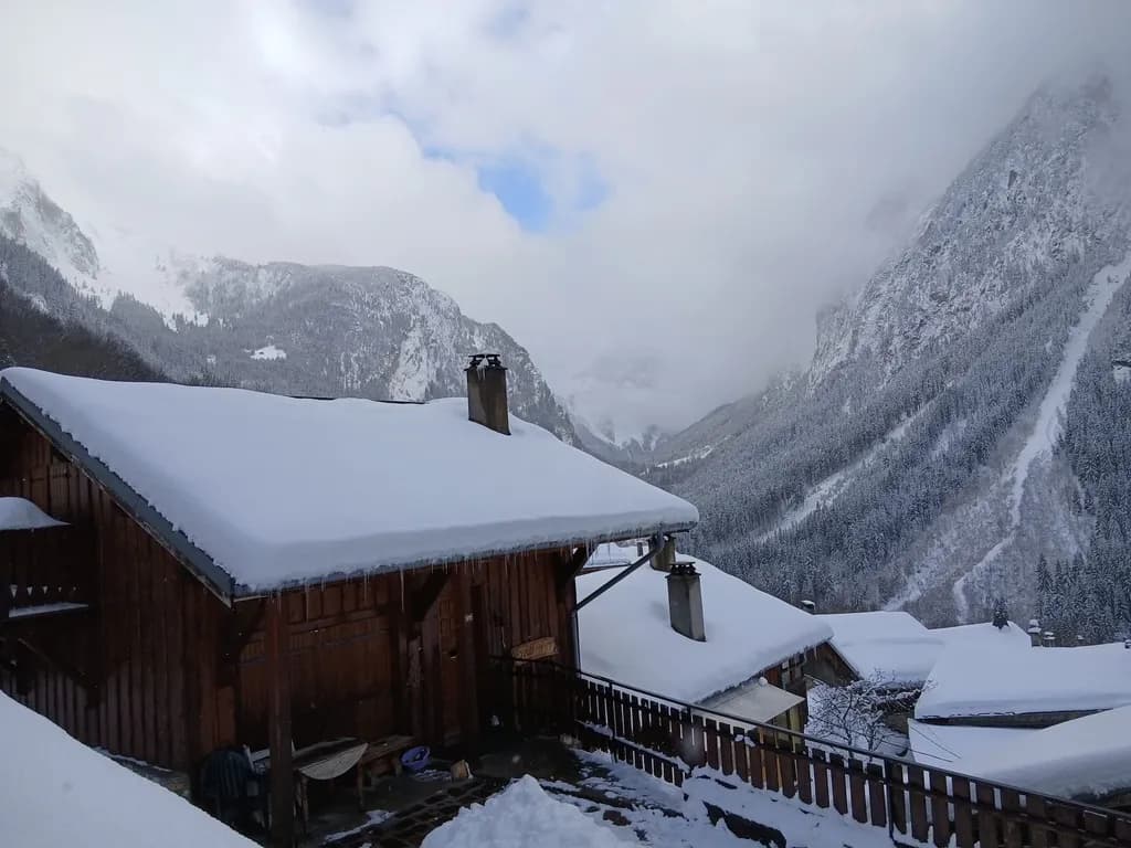 Vue hivernale sur les toits enneigés et la vallée depuis le balcon