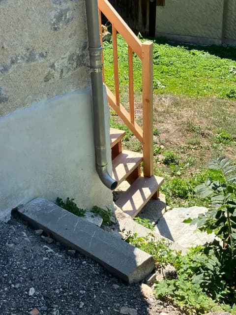 Escalier en bois extérieur menant à une terrasse en pierre