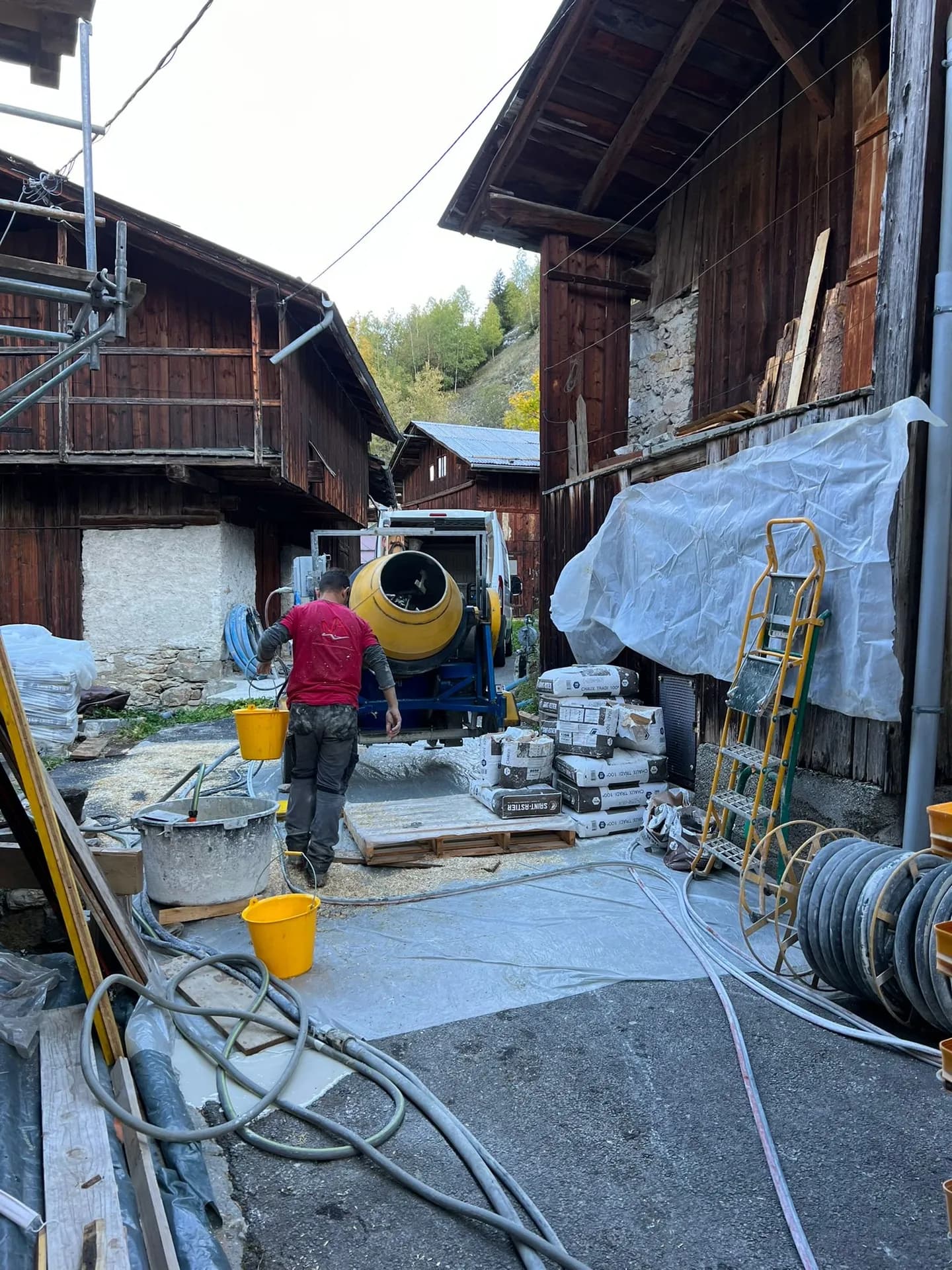 Chalet en bois avec deux personnes préparant un barbecue sur terrasse en pierre