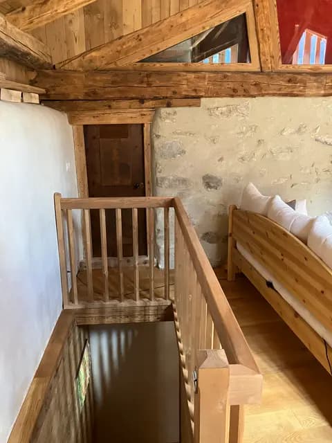 Escalier en bois brut menant à l'étage sous charpente apparente