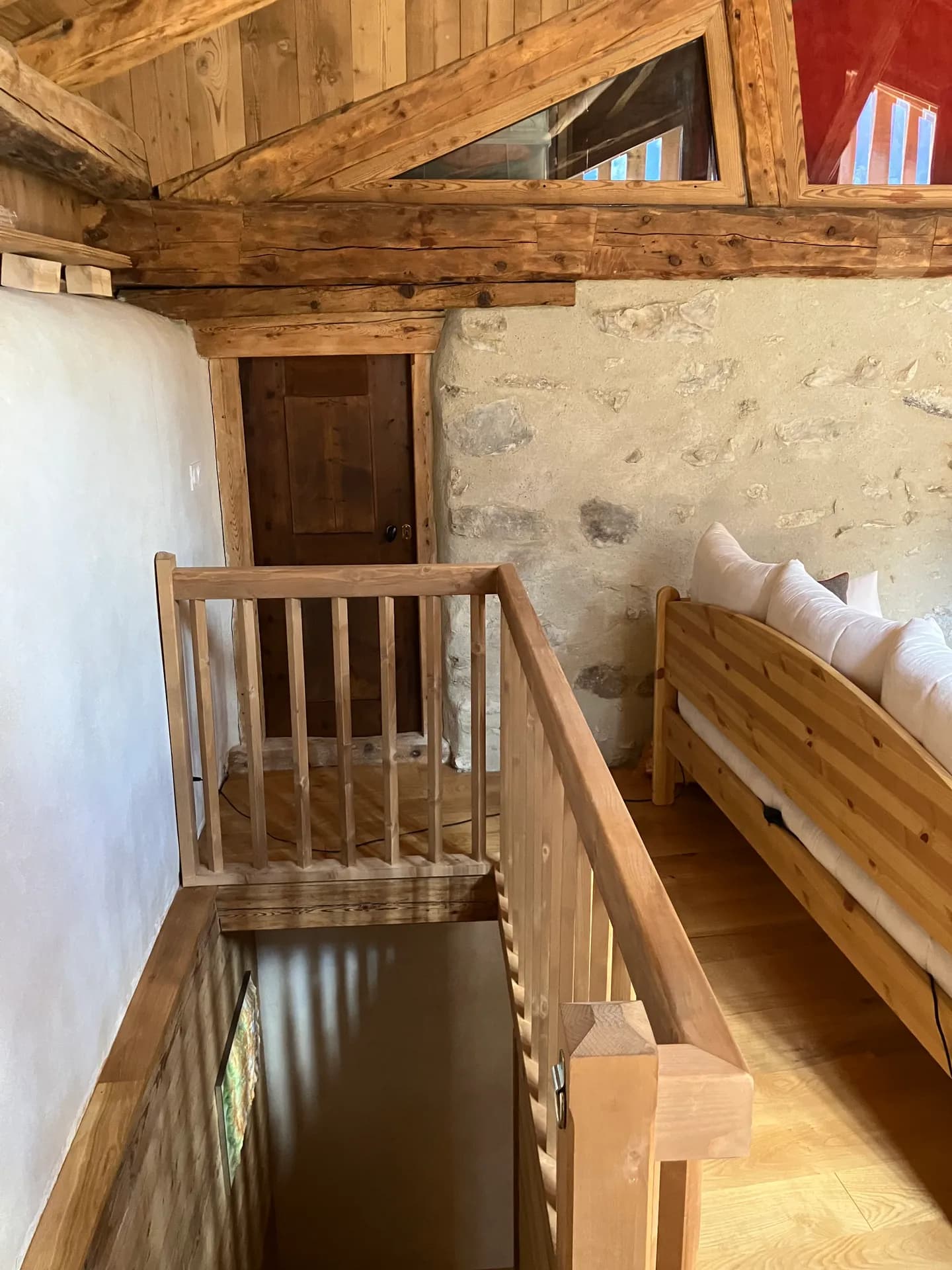 Escalier en bois brut menant à l'étage sous charpente apparente