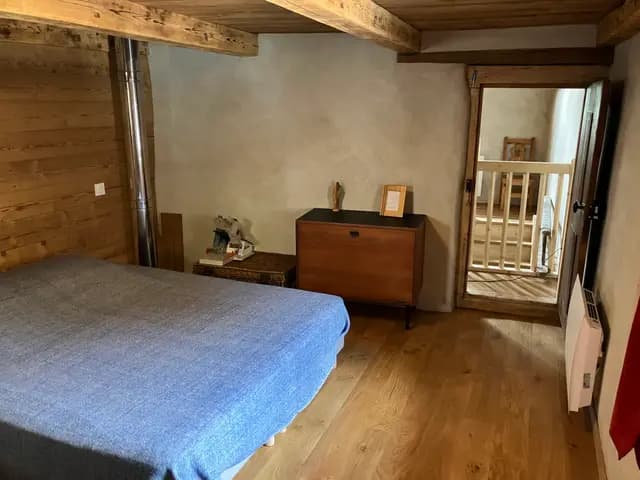 La chambre de la suite ouverte sur le palier et sa rambarde en sapin