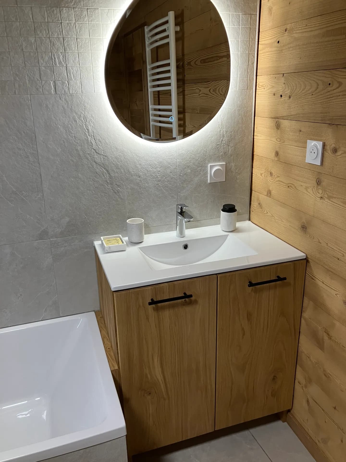 Lavabo sous miroir et meuble de rangement en bois dans salle d'eau