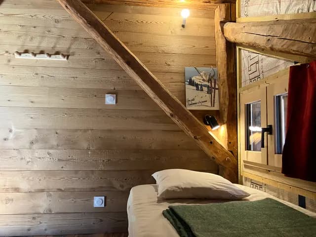 Lit en bois sous poutres apparentes avec couverture à carreaux