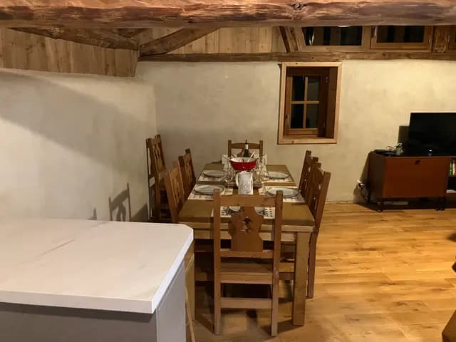 Salle à manger sous charpente apparente avec table en bois et chaises