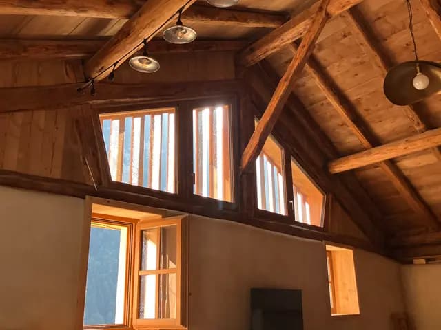 La charpente du séjour cathédrale au soleil couchant, fenêtres du pignon sur la forêt