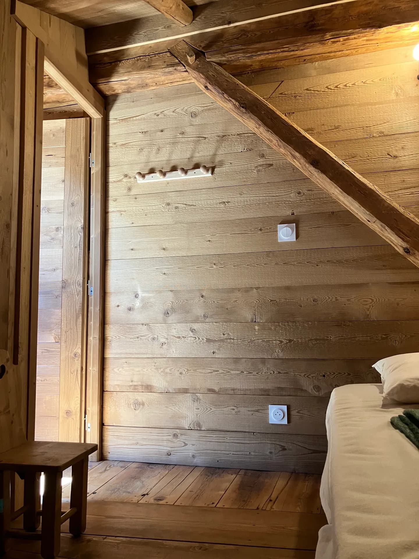 Poutres apparentes en bois clair sous plafond mansardé