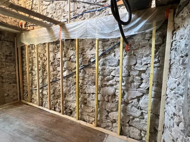 Mur en pierre apparente avec étagères en bois et éclairage intégré