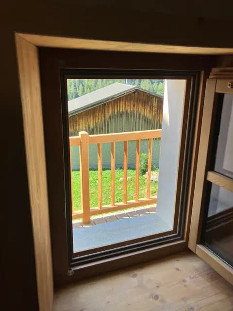 Fenêtre en angle avec vue sur la forêt et la montagne depuis le salon