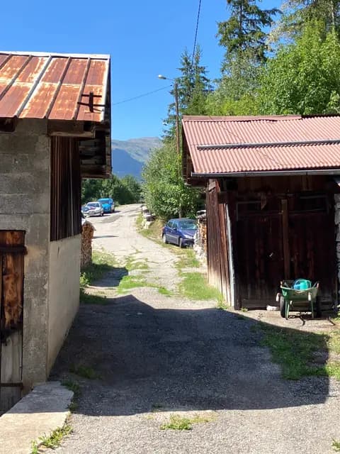 Terrasse en bois avec vue sur route de montagne et voitures garées