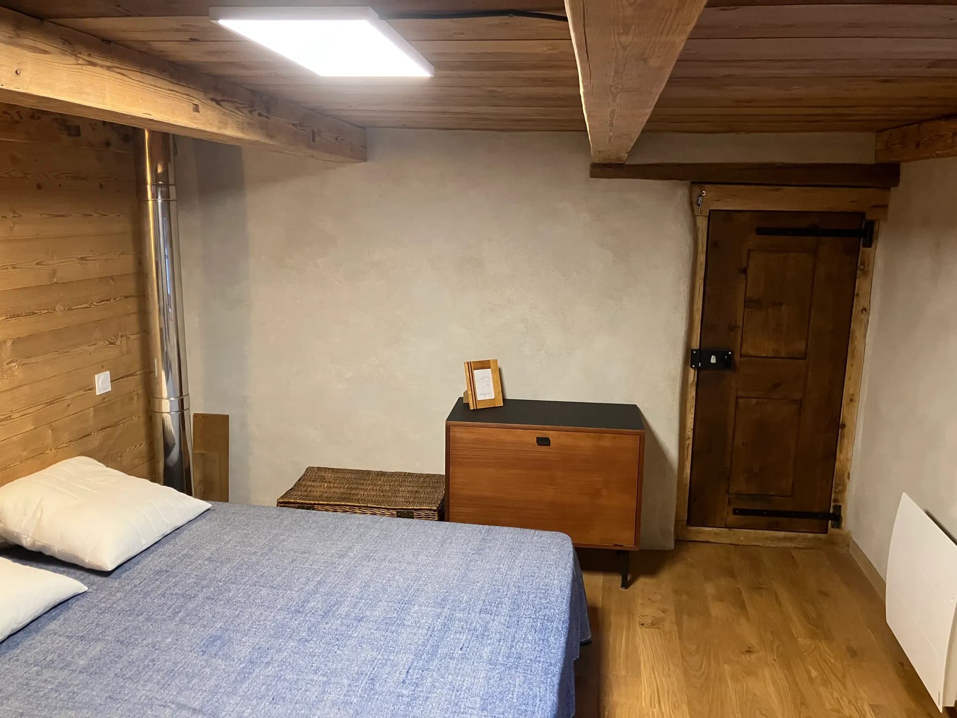 Le lit face à la commode vintage et à la vieille porte en bois d'origine