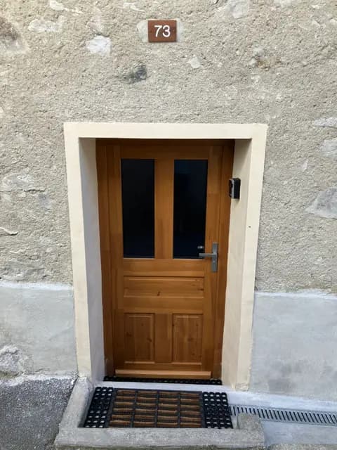 Porte en bois clair avec numéro 73 et boîte aux lettres