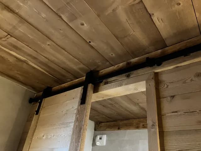 Les rails des portes coulissantes en vieux bois, sous le plafond en sapin