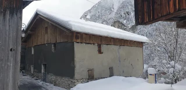 Chalet en bois sous la neige avec cheminée et banc
