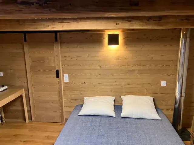 La tête de lit lambrissée de la suite, applique et porte coulissante en vieux bois