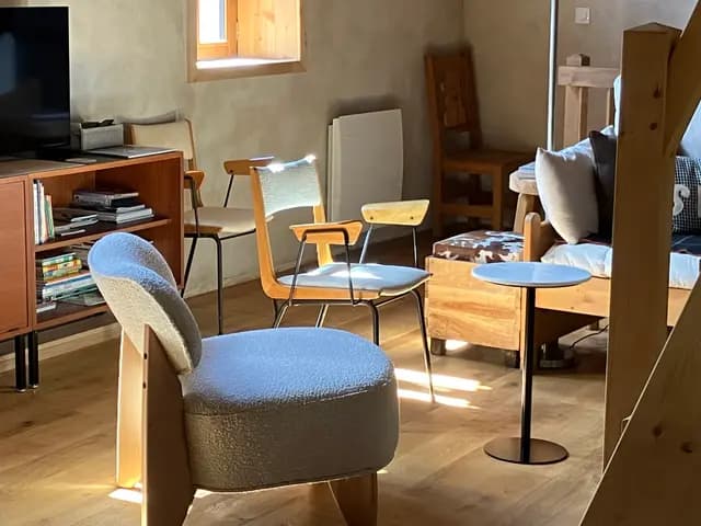Table en bois avec quatre chaises et pouf bleu dans pièce à vivre