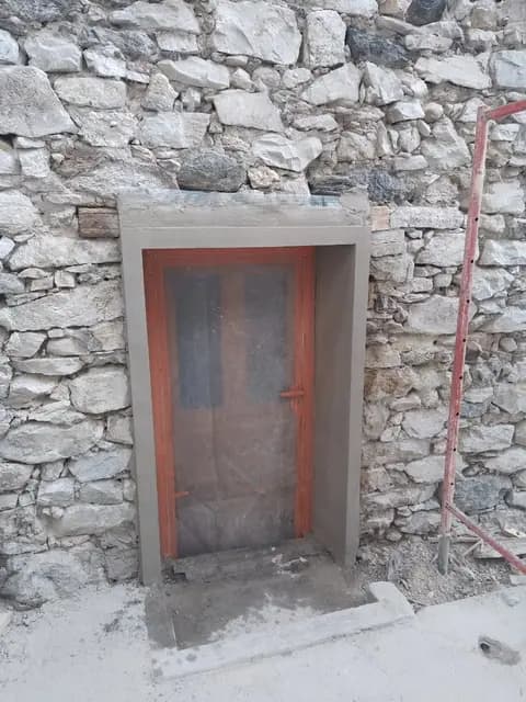 Porte rouge encadrée de pierres apparentes dans un chalet savoyard
