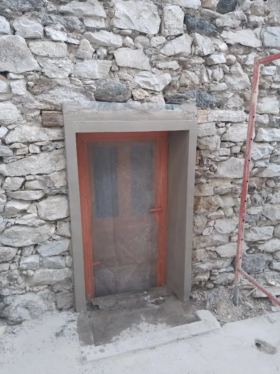 Porte rouge encadrée de pierres apparentes dans un chalet savoyard
