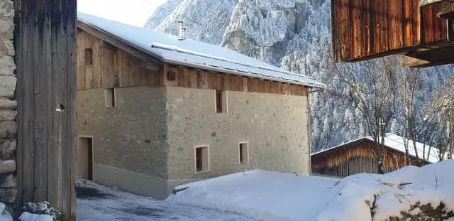 Petite place de parking enneigée devant chalet en bois