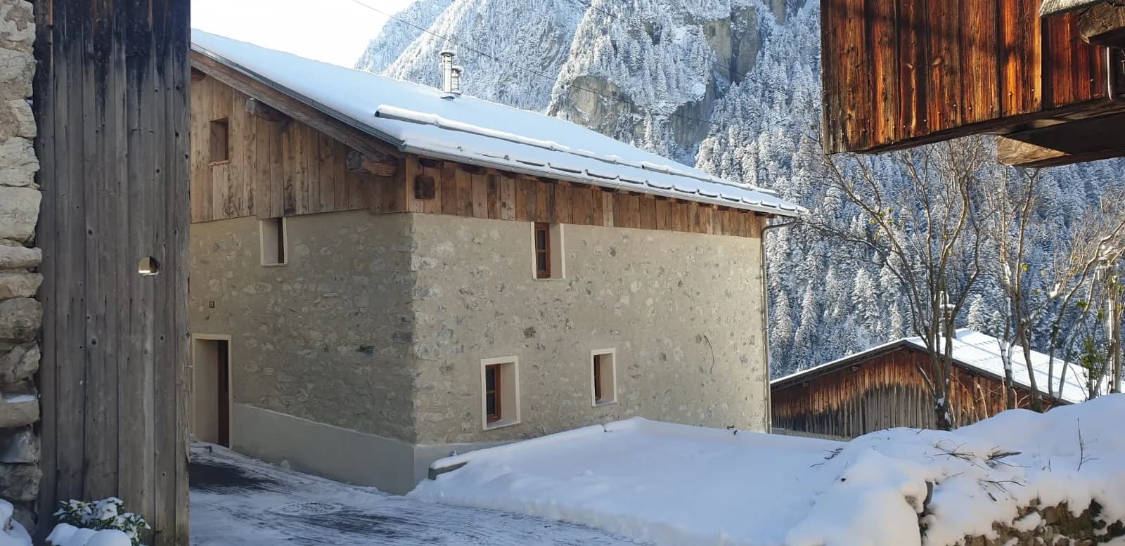 Petite place de parking enneigée devant chalet en bois
