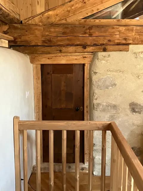 Escalier en bois brut avec porte en bois clair en haut