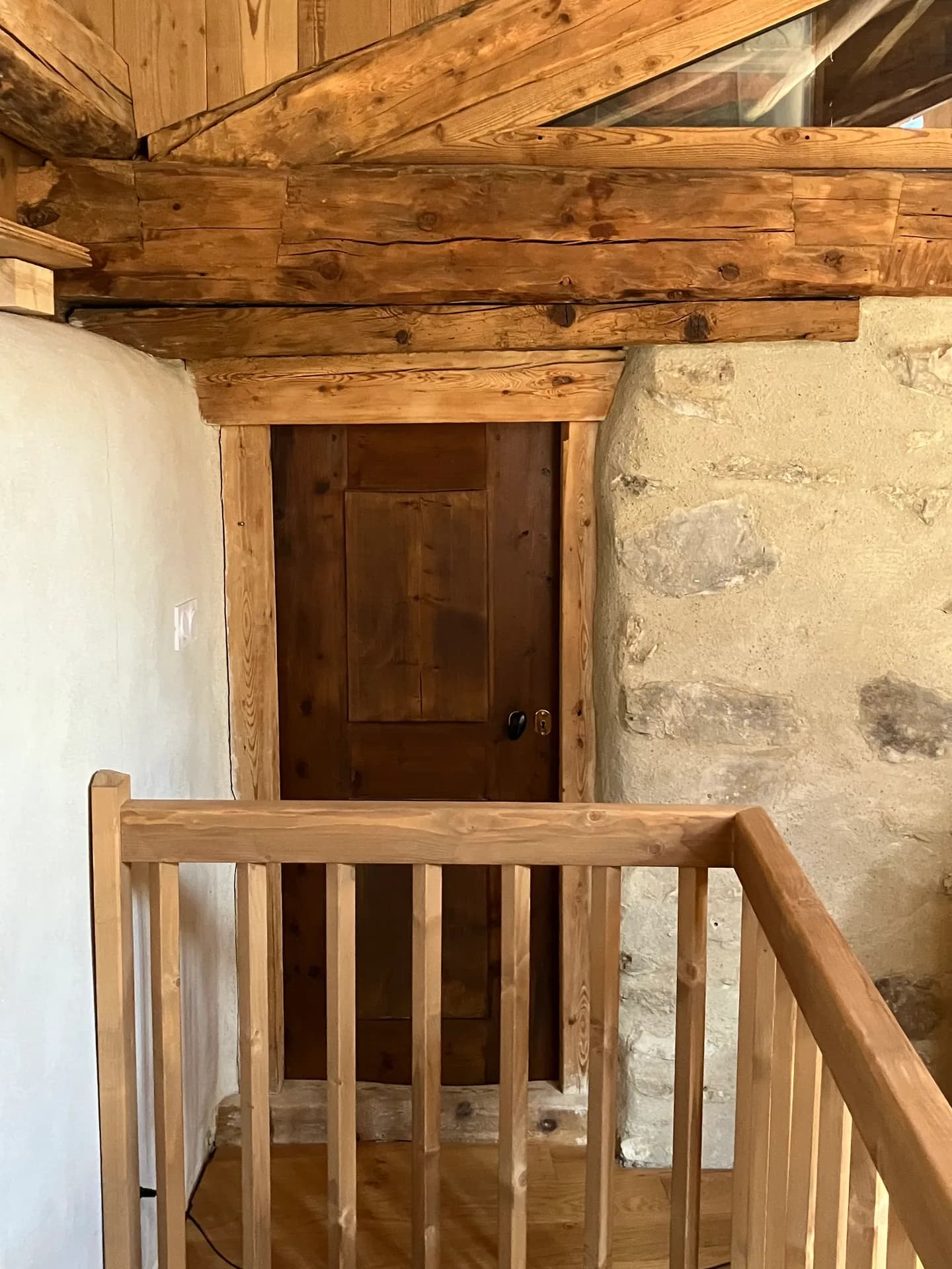 Escalier en bois brut avec porte en bois clair en haut