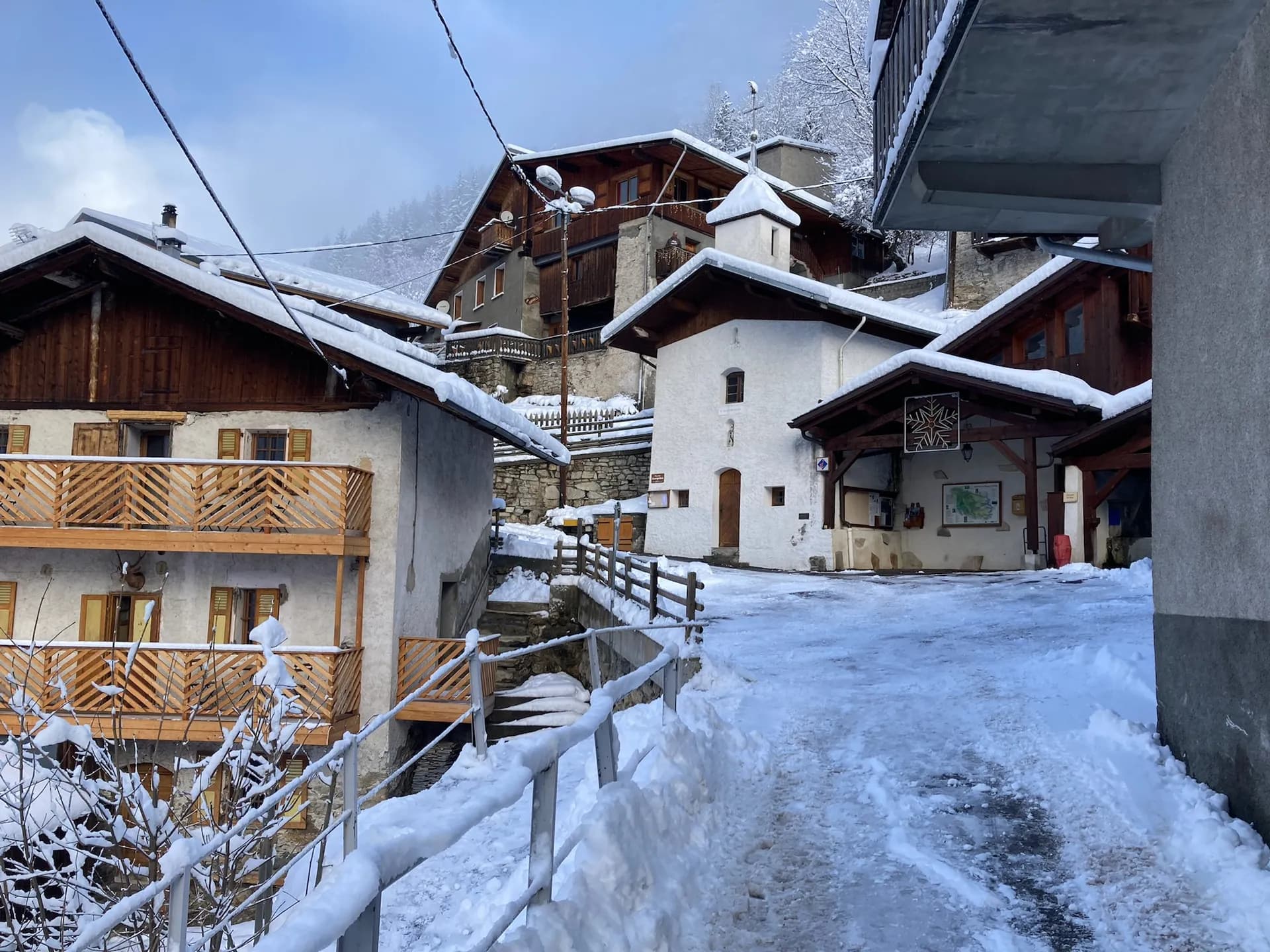 Village de montagne enneigé avec chalets en bois et bancs sous la neige