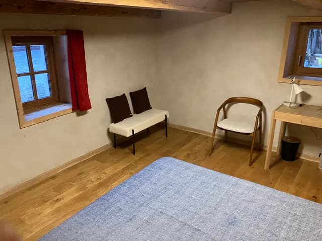 L'espace salon de la suite : banquette, fauteuil et bureau sous les poutres