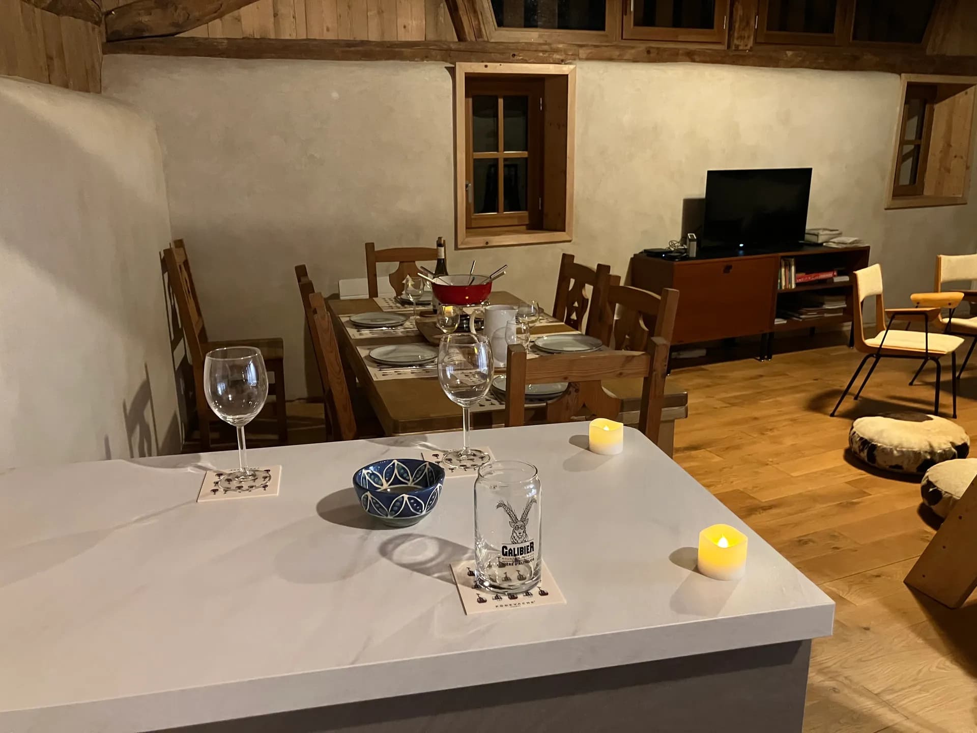 Cuisine ouverte avec évier, verres et bouilloire sur plan de travail en bois
