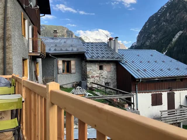 Balcon en bois avec vue sur montagne et chalet en pierre