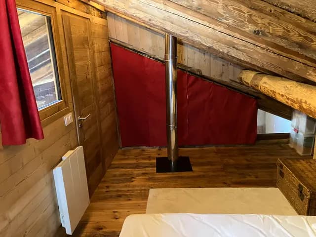 Escalier en bois rouge menant à l'étage sous charpente apparente