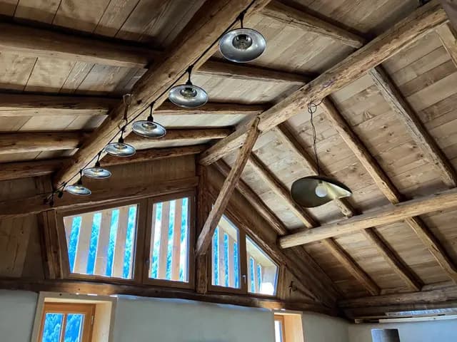 Poutres apparentes et lustre en bois dans pièce à baies vitrées