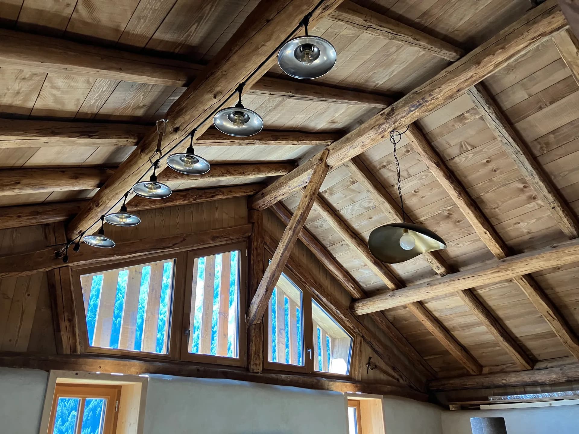 Poutres apparentes et lustre en bois dans pièce à baies vitrées