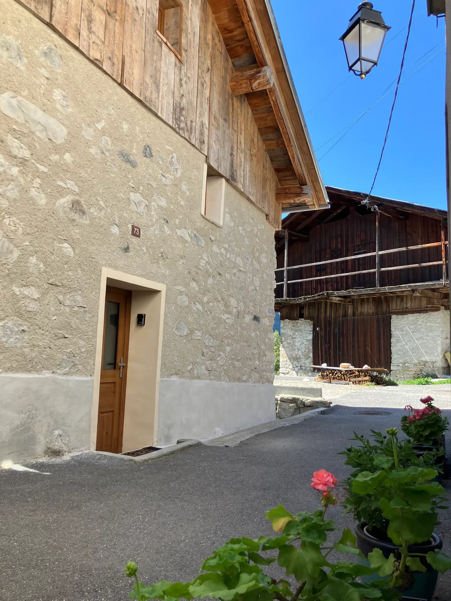 Entrée du chalet avec porte en bois et jardinières fleuries