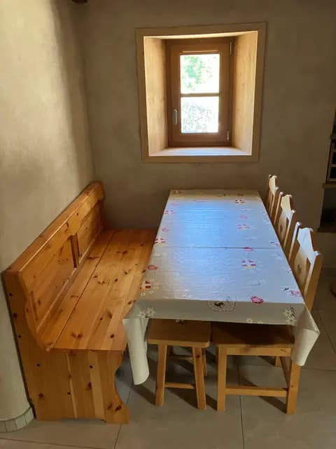 Table en bois avec vaisselle et bougies, vue depuis la cuisine
