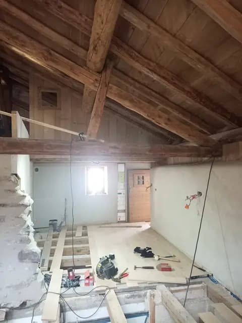 Escalier en bois menant à l'étage sous charpente apparente