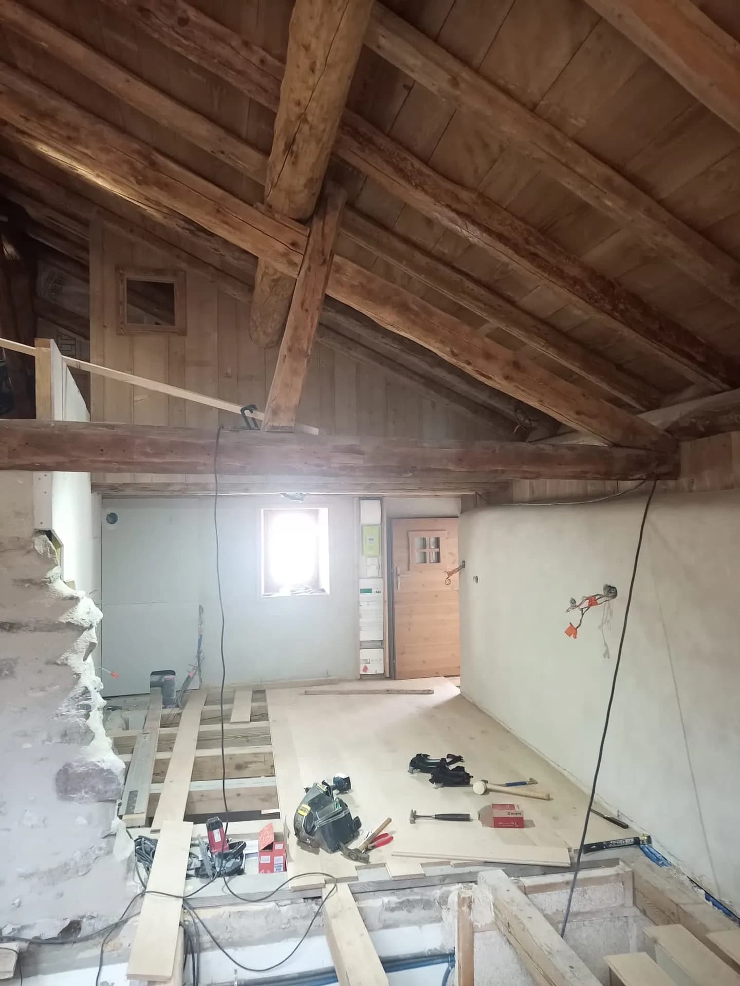 Escalier en bois menant à l'étage sous charpente apparente