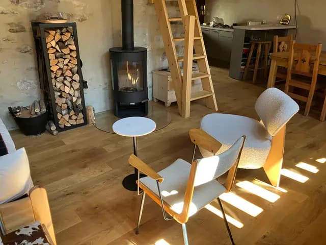 Coin repas avec table en bois et chaises, poêle à bois et cuisine équipée